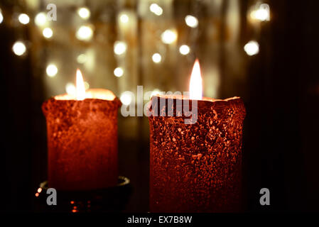 Due candele arancione sopra le luci di Natale Foto Stock