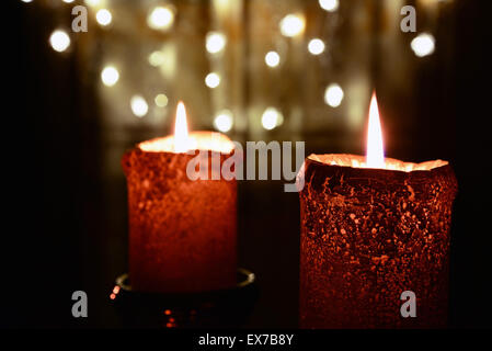 Due candele arancione sopra le luci di Natale Foto Stock