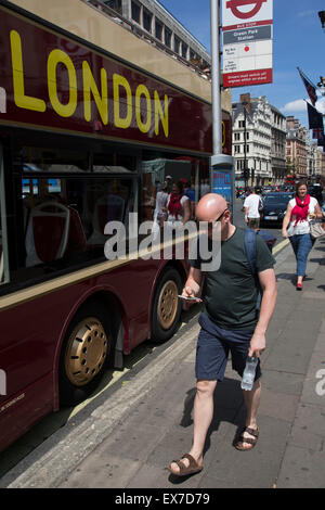 Estate a Londra, Inghilterra, Regno Unito. I turisti a piedi lungo uno di Londra più famose strade, Piccadilly a Mayfair. Piccadilly è una delle più vaste e strade più dritte nel centro di Londra. È la posizione di numerosi importanti punti di riferimento di Londra ed edifici, compresi Fortnum & Mason, la Royal Academy e il Ritz Hotel. Foto Stock