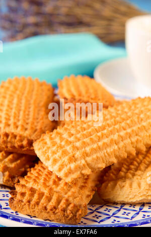 Ingrandimento di una piastra con una pila di biscotti fatti in casa e una tazza di caffè o di tè in background in un set table Foto Stock