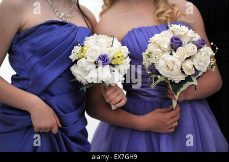 Pontypridd, Wales, Regno Unito. Chiudere fino a 2 bridesmaids in viola abiti di raso bianco con bouquet di rose. © Becky Matthews Foto Stock