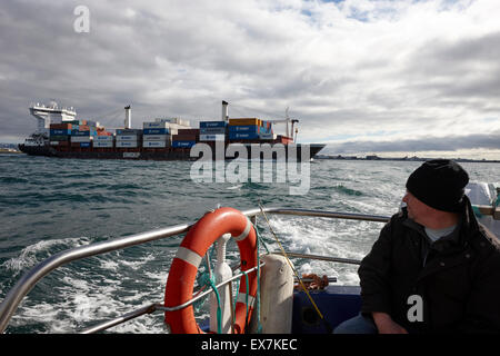 Grande contenitore eimskip nave passando dietro le barche più piccole Reykjavik Islanda Foto Stock