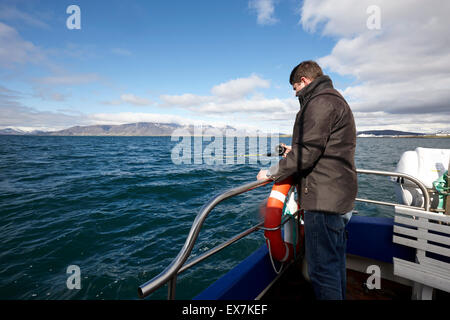 L'uomo seafishing con un'asta e una linea su una barca charter Reykjavik Islanda Foto Stock