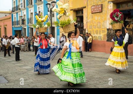 Donne in costume tradizionale danza portante e cesti di fiori sulle loro teste che conduce a una sfilata in un festival in Messico Oaxaca Foto Stock