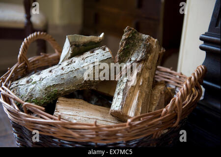Ross-on-Wye, Herefordshire, UK. Logs impilati in un cesto di vimini nella parte anteriore di un incendio in una casa di campagna © Becky Matthews Foto Stock