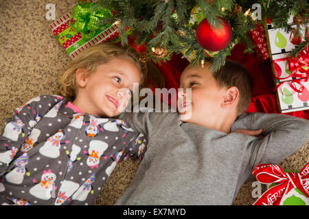 Fratello (6-7) e sorella (6-7) giacenti da albero di Natale Foto Stock