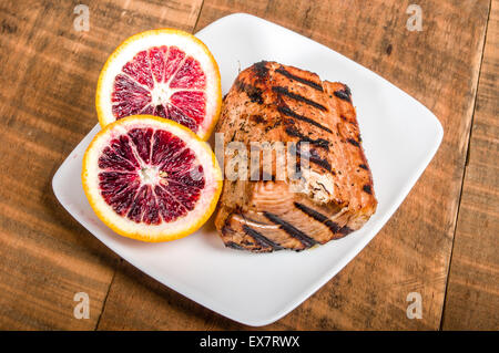 Bistecca di tonno alla griglia con sangue salsa arancione sulla piastra Foto Stock