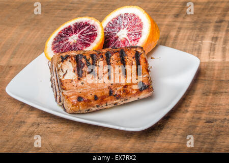 Bistecca di tonno alla griglia con sangue salsa arancione sulla piastra Foto Stock