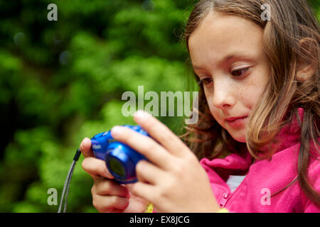 Ragazza è guardando le immagini sulla fotocamera digitale compatta display Foto Stock