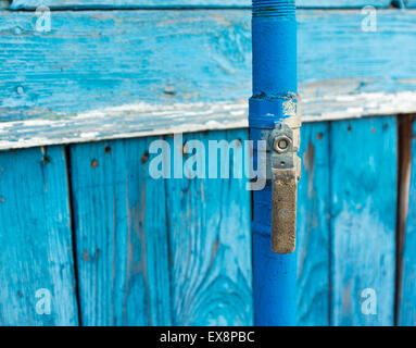 Il blu della tubazione del gas con la porta passa da una parete in legno Foto Stock