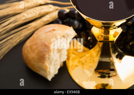 Offerta religiosa, il cristianesimo, oro calice con il vino, uva, pane e le colture Foto Stock