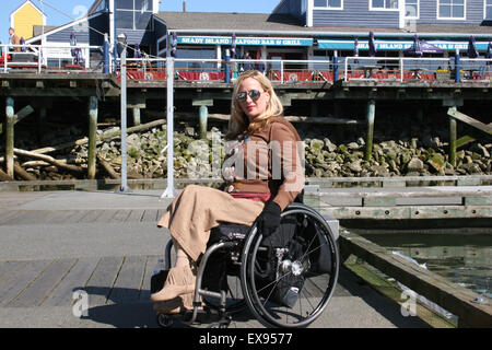 Donna che utilizza una sedia a rotelle su un molo sul fiume Fraser Foto Stock