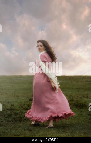 Una ragazza in un abito rosa è camminare su per una collina Foto Stock