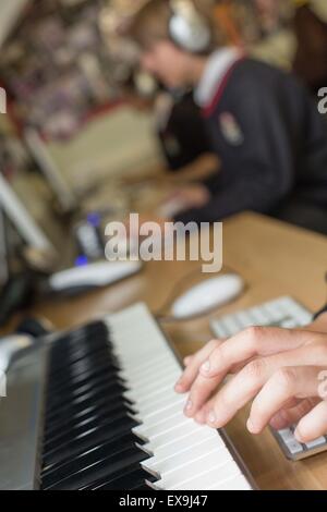 Scuola gli studenti in uniforme, utilizzando un software musicale e le apparecchiature nella lezione Foto Stock