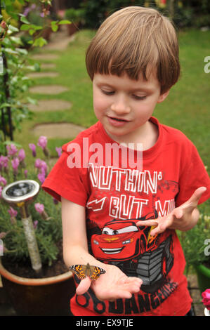 Un ragazzino con un dipinto di lady butterfly Foto Stock