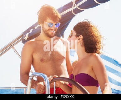 Allegro giovane la guida in barca a vela, bello ragazzo e ragazza carina ridendo e guardando con amore gli uni sugli altri Foto Stock