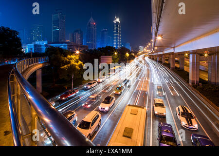 Cina, Shanghai, immagine sfocata di auto e il traffico sul bus di Yan'an Road sotto il cavalcavia di calcestruzzo sulla sera d'inverno Foto Stock