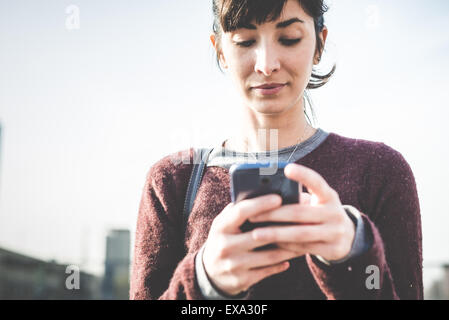 Giovane bella donna parigamba utilizzando smart phone in città Foto Stock