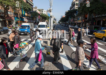 Asia, Taiwan, Taipei, pedoni folla insieme mentre si cammina attraverso crosswalk vicino al Mercato di Dongmen sul soleggiato al mattino invernale Foto Stock