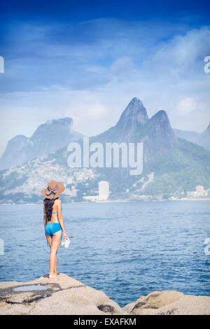 Un 20-25 anni brasiliano di giovane donna in piedi sull'Arpoador rocce, Rio de Janeiro, Brasile Foto Stock