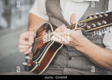 Chiudere fino a mani hipster uomo giocando il mandolino nella città Foto Stock