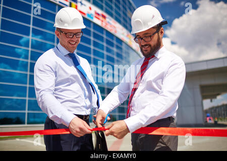 Architetto felice il taglio di nastro rosso all apertura ufficiale di nuova costruzione Foto Stock