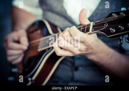 Chiudere fino a mani hipster uomo giocando il mandolino nella città Foto Stock