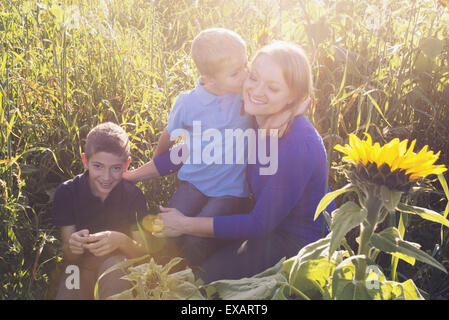 Madre e figli di trascorrere del tempo insieme in un campo di girasoli Foto Stock