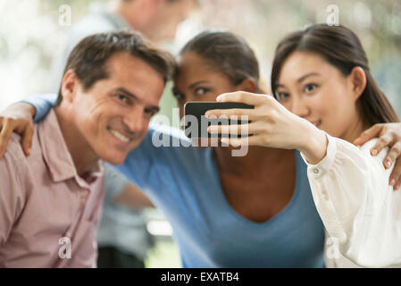 Donna Fotografa se stessa e gli amici con lo smartphone Foto Stock