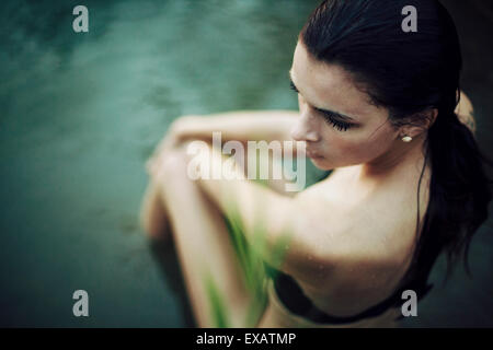 Giovane donna siede nell'acqua Foto Stock