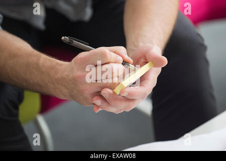 La scrittura della nota sul cuscinetto adesivo Foto Stock