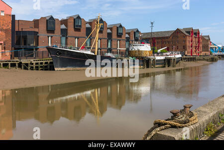 Obsoleta nave spiaggiata fango sulla riva del fiume scafo con vista della banchina di edifici e il fiume di Hull, Humberside, UK. Foto Stock