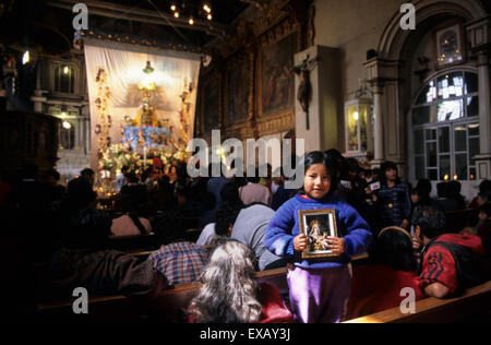 Paucartambo, Perù. Piccola ragazza con un immagine della Vergine del Carmen nella chiesa prima della processione. Foto Stock