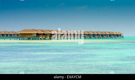 I bungalow sull'acqua di un'isola resort si estendono in laguna in Maldive Foto Stock