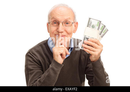 Senior gentleman holding tre pile di denaro e tenendo un dito sulle sue labbra isolato su sfondo bianco Foto Stock
