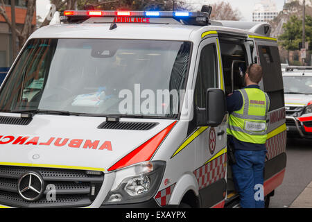 Nuovo Galles del Sud ambulanza partecipando ad una emergenza in Lee Street, Sydney, Australia. Paramedic partecipando al suo paziente. Foto Stock