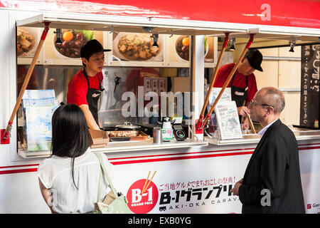 I clienti di attendere in linea per ordinare il loro cibo in ''B-1 Grand Prix Cafe'' sotto il cavalcavia di Akihabara station sulla luglio 10, 2015, Tokyo, Giappone. B-1 cibo si riferisce al locale di classe B cucina gourmet che è popolare in Giappone per la sua economici e piatti deliziosi. Il B-1 Grand Prix caffetteria (Aki-oka Caravane) aperto per una sola notte e introdotto nove tipi di piatti gourmet inclusi Towada Barayaki (nella prefettura di Aomori) e Fujinomiya Yakisoba (Prefettura di Shizuoka) provenienti da tutto il Giappone. (Foto di Rodrigo Reyes Marin/AFLO) Foto Stock