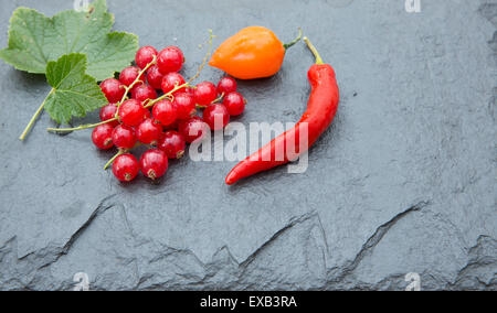 Ribes rosso e peperoncino sul piatto di ardesia. Foto Stock