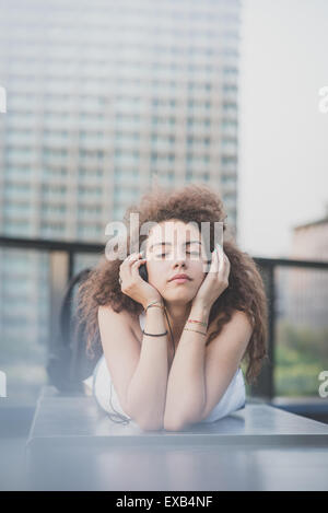 Giovane bella lunghi capelli ricci hipster donna l'ascolto di musica con il tablet in città Foto Stock