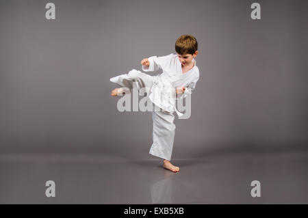 Il Karate boy in bianco kimono ritratto in studio su sfondo grigio Foto Stock