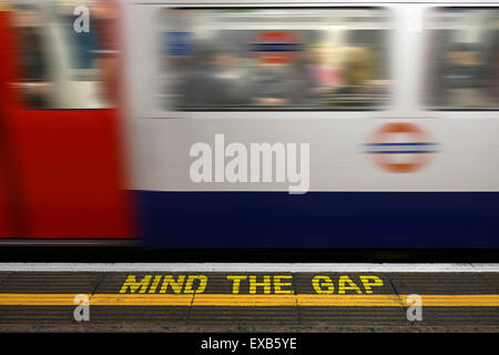 Mente il divario segno di avvertimento sul bordo della piattaforma di una stazione della metropolitana di Londra. Foto Stock