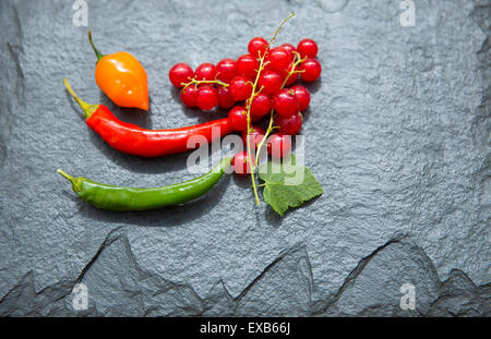 Ribes rosso e peperoncino sul piatto di ardesia. Foto Stock