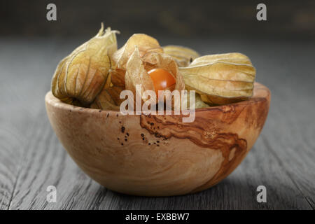 Physalis frutto nella tazza di olive su oak tavolo in legno Foto Stock