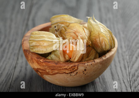 Physalis frutto nella tazza di olive su oak tavolo in legno Foto Stock