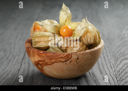 Physalis frutto nella tazza di olive su oak tavolo in legno Foto Stock