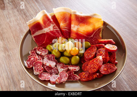 Le tapas di Spagna con prosciutto olive e salsiccia chorizo su sfondo di legno Foto Stock