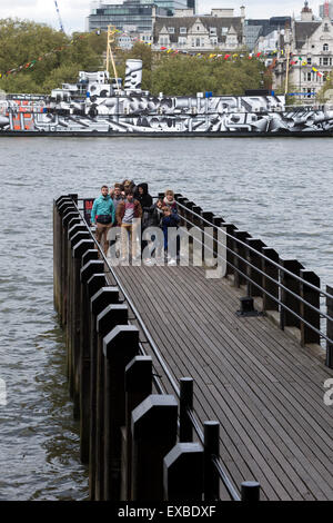 I turisti alla torre di osso Pier con HMS Presidente coperto in WWI dazzle camouflage sul Fiume Tamigi, Londra, Inghilterra, Regno Unito. Foto Stock