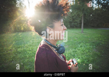 Bella black capelli ricci donna africana ascolto di musica con cuffie in città Foto Stock