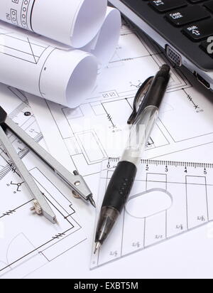 Rotoli di schemi elettrici, disegni di costruzione della casa, accessori per disegno e laptop, disegni Foto Stock