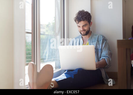 Bello hipster l uomo moderno designer che lavora a casa utilizzando portatile a casa Foto Stock